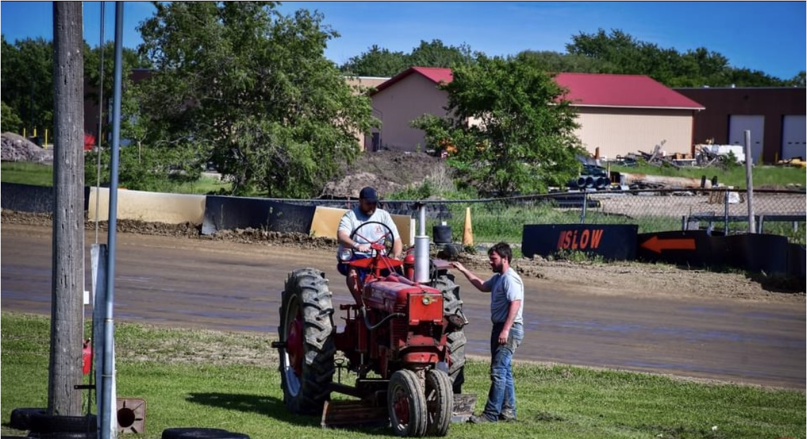 men mowing track grass with tractor